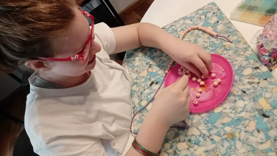 Close up of a learner beading a necklace
